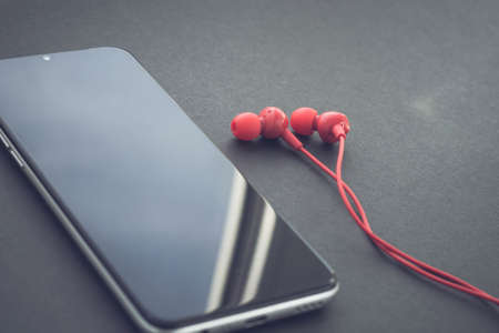 Mobile phone and headphones. Cell phone with black display.の写真素材