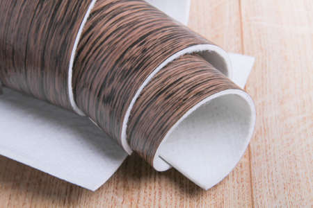 Linoleum. Roll of linoleum on a black background. floor coverings. Laying floor coverings. Wood texture on a roll. The sample is rolled up.の写真素材