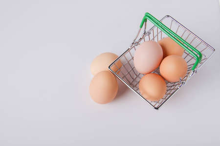 Chicken eggs in a shopping cart. Eggs in the store. Fresh food on the shelf. food basket. Close-up on a white background top view.の写真素材