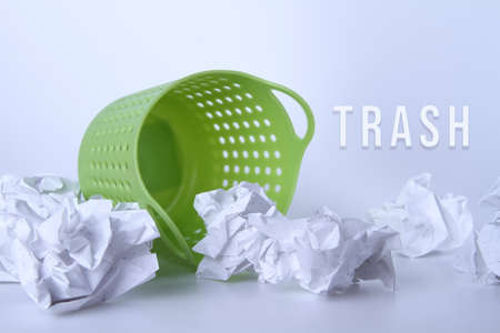 Green trash can. Full basket. Crumpled paper in a basket. A mountain of garbage is scattered on the table.の写真素材
