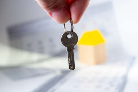Keys in hand and house. Handing over the keys to the apartment.の写真素材