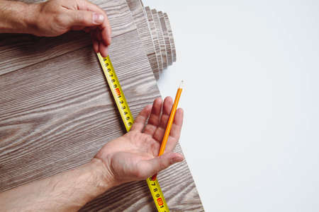 Measurement of linoleum on a cut. Man cuts linoleum. Tape measure and a man's hand with a piece of flooring.の写真素材