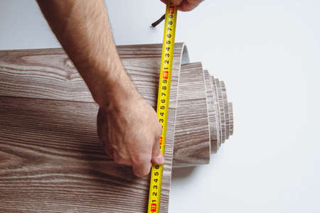 Measurement of linoleum on a cut. Man cuts linoleum. Tape measure and a man's hand with a piece of...