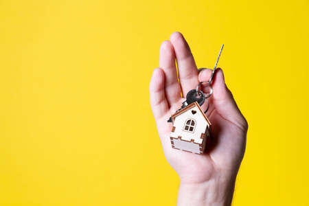 Buying a house The buyer receives the key to the property. Mortgage apartment. Keys and a small wooden house in hand. Handing over the keys to the owner.の写真素材
