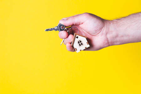 Buying a house The buyer receives the key to the property. Mortgage apartment. Keys and a small wooden house in hand. Handing over the keys to the owner.の写真素材