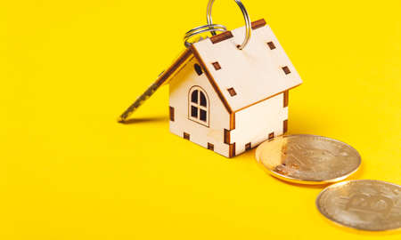 Buying real estate for cryptocurrency. housing and bitcoins. Coins and house keys. Small wooden house and bitcoin coin.の写真素材