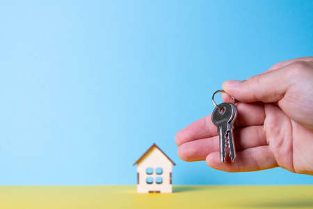 Buying a house The buyer receives the key to the property. Mortgage apartment. Keys and a small wooden house in hand. Handing over the keys to the owner.の写真素材