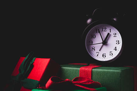 Waiting for the new year. Clock with an alarm clock and a gift. Happy New Year. Christmas presents.の写真素材