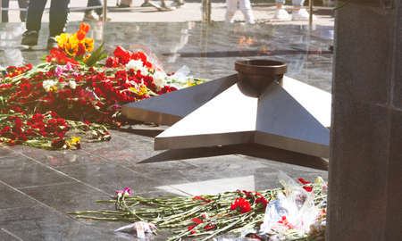 Commemorative memorial. Laying flowers at the eternal fire. Tribute to the memory of the fallen soldiers. Flowers and a soldering iron for soldiers.の写真素材
