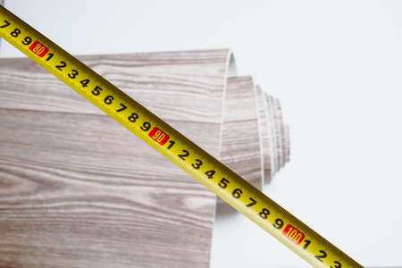 Measurement of linoleum on a cut. Man cuts linoleum. Tape measure and a man's hand with a piece of flooring.の写真素材