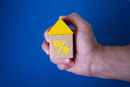 Cubes in the form of a house in hand. Saving at home. Acquisition of housing abroad. under protection. The housing deal went through.の写真素材