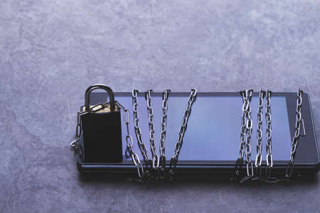 Prohibited applications on a smartphone. Blocking dangerous applications. Bypass blocking with vpn. Phone and chain lock. Chain around and locked padlock. Limited access to user data.の写真素材