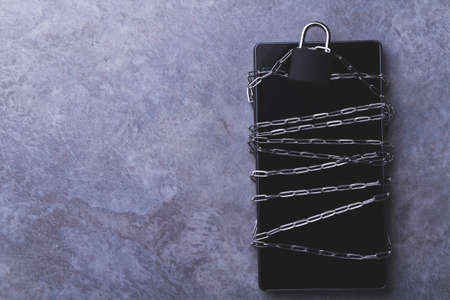 Prohibited applications on a smartphone. Blocking dangerous applications. Bypass blocking with vpn. Phone and chain lock. Chain around and locked padlock. Limited access to user data.の写真素材