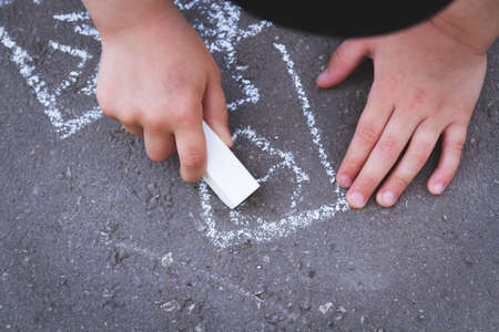 Children draw with chalk on the road. Children's creativity on the street. entertainment in nature.