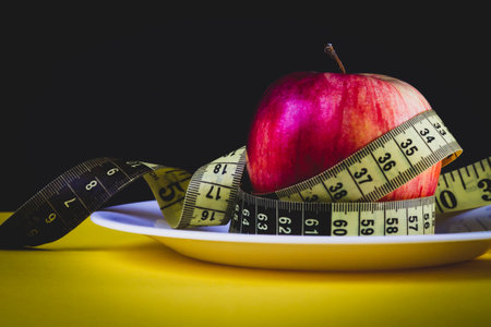 Apple as a means for weight loss. Obesity problem. Fruit diet. Apple and measuring tape.の写真素材