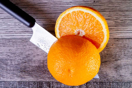 Slicing oranges top view. There is a knife and pieces of orange on the table. Sliced orange halves. Juice freshly squeezed.の写真素材
