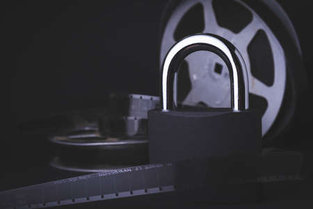 Movie screening ban. Forbidden film. Indoor cinema.Film reel and padlock on a black background. Limited screening of the film in cinemas.の写真素材