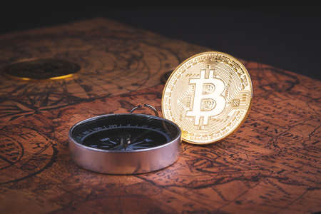 Compass and bitcoin. Travel and cryptocurrencies. Buying tickets with bitcoins. Alternative currency and travel. Coin and compass on the map.の写真素材