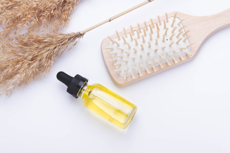 Oil for hair growth. Therapeutic oil to activate hair growth. Comb on white background. Hair care. Beauty and health.の写真素材