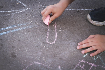 Children draw with chalk on the road. Children's creativity on the street. Entertainment in nature.の写真素材