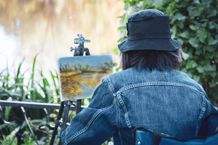 Girl artist paints picture in nature. Painting with paints on canvas..の写真素材