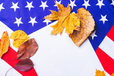 Clean white sheet of paper on background of american flag with dry yellow leaves along edge..の写真素材