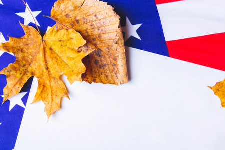 Clean white sheet of paper on background of american flag with dry yellow leaves along edge..の写真素材