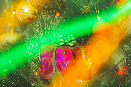 New Year's gift in a bright package against the background of Christmas decorations and bright lights of the garland..の写真素材