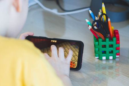 Phone in hands of child. Little boy playing mobile games on smartphone. Hand closeup..の写真素材