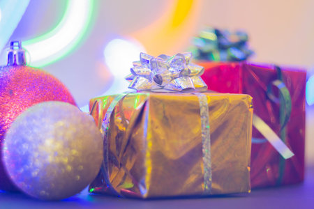 New Year's gift in a bright package against the background of Christmas decorations and bright lights of the garland..の写真素材