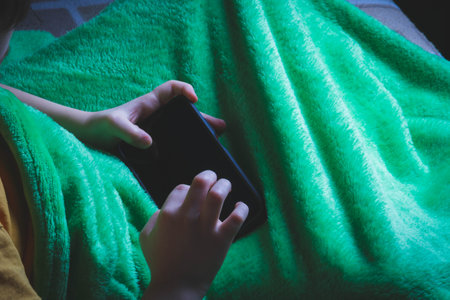 Phone in hands of child. Little boy playing mobile games on smartphone. Hand closeup..の写真素材