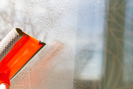 Window washing. Cleaning the window with a brush and foam. The concept of cleanliness and cleaning..の写真素材