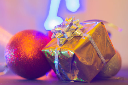 New Year's gift in a bright package against the background of Christmas decorations and bright lights of the garland..の写真素材