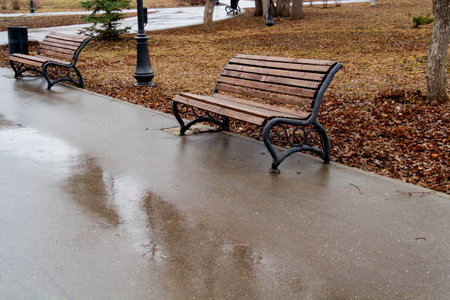 Wooden bench in the spring park. Bright spring sun and snow in the park. Place to rest for a walk. Morning walk..の写真素材