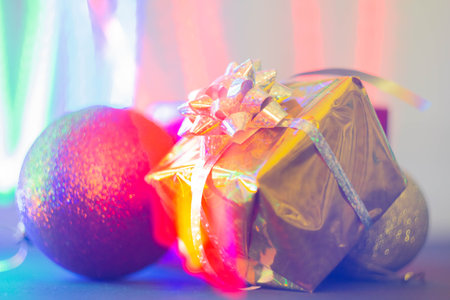 New Years gift in a bright package against the background of Christmas decorations and bright lights of the garland..の写真素材