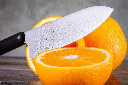 Slicing oranges side view. A man cuts an orange with a knife. The process of making juice from fruits. Knife and orange.の写真素材