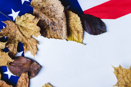 Clean white sheet of paper on background of american flag with dry yellow leaves along edge..の写真素材