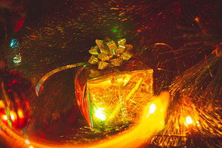 New Year's gift in a bright package against the background of Christmas decorations and bright lights of the garland..の写真素材