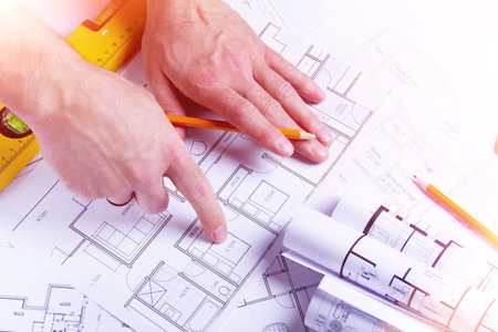 Builder's hands on the background of a house plan. Construction planning. Drawing up an estimate..の写真素材
