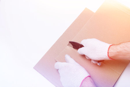 Stretch film and cardboard packaging on a white background top view. Packaging of goods. A knife for cutting cardboard..の写真素材