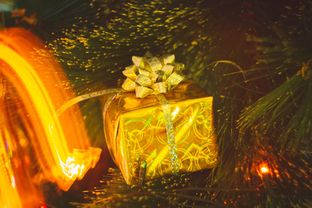 New Year's gift in a bright package against the background of Christmas decorations and bright lights of the garland..の写真素材