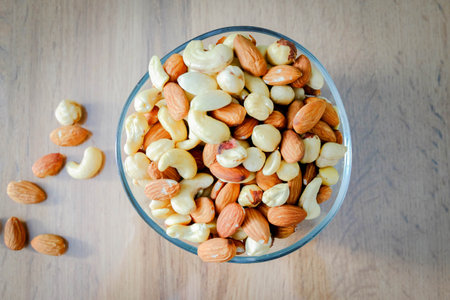 Cashews, peanuts and almonds on a plate. Nuts on the table in the bright rays of the sun..の写真素材