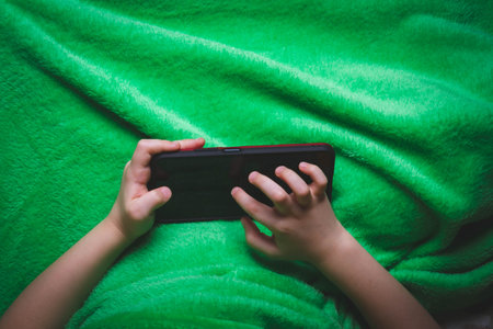 Phone in hands of child. Little boy playing mobile games on smartphone. Hand closeup..の写真素材