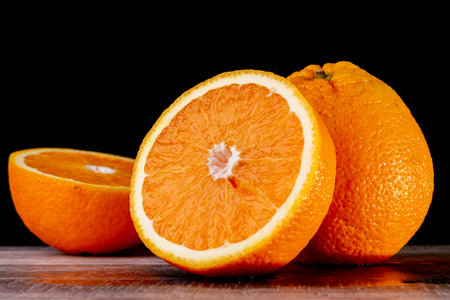 Half an orange. Two halves of fruit on a wooden table. Fresh and ripe fruit is cut on a dark...