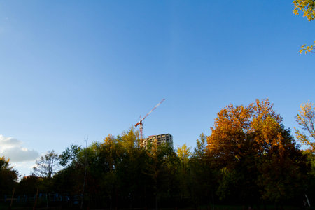 Construction crane towers over house under construction against blue sky..の写真素材