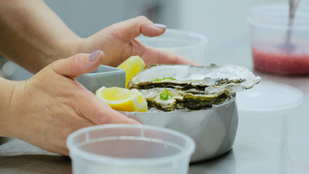 Oysters on ice in a metal bowl. Cooking oysters in the restaurant kitchen. Close-up of oysters in the kitchen. The cook serves a dish with oystersの写真素材