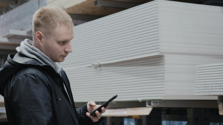 A man in a hardware store chooses wooden sheets of osb. The buyer in the store chooses chipboard. Buying plywood at a hardware store. Blockboards in a hardware storeの写真素材