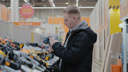 A man in a hardware store chooses electrical goods. The buyer in the store chooses a screwdriver....