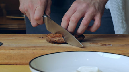 Close-up of a juicy freshly cooked steak. The male chef makes the composition of the dish for serving. Professional chef in the restaurant kitchen serving a dishの写真素材