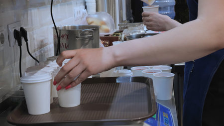 The chef pours drinks into paper cups, the drink is poured into disposable glasses, cool drink, charity kitchen, drink preparation.の写真素材
